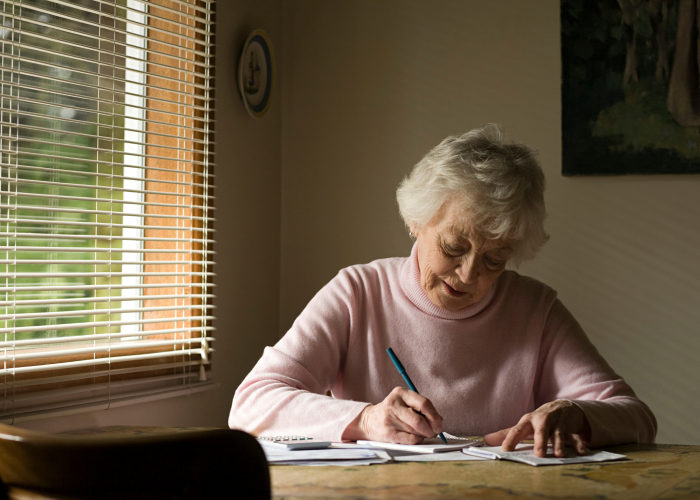 senior-woman-writing-at-table-in-home